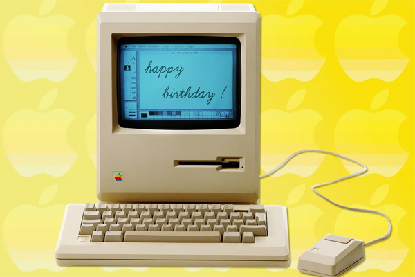 An Apple Macintosh computer showing “happy birthday!” on the screen.